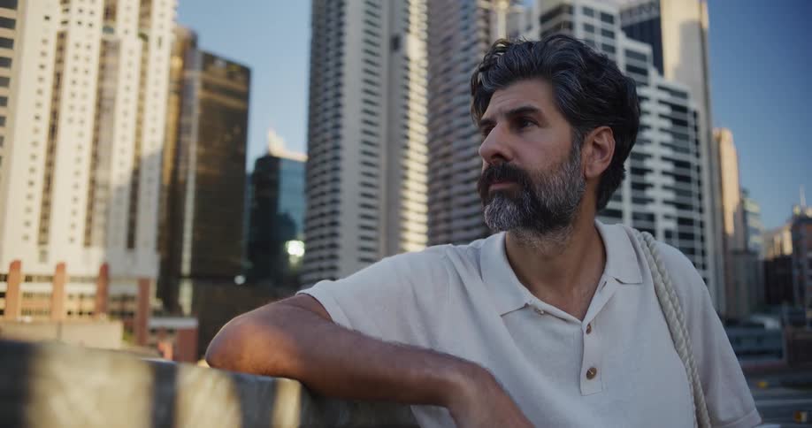 A man leans against a wall and stares at a city