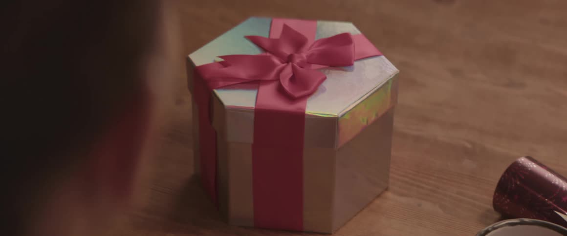 A white person looks at a gift on a table and fidgets