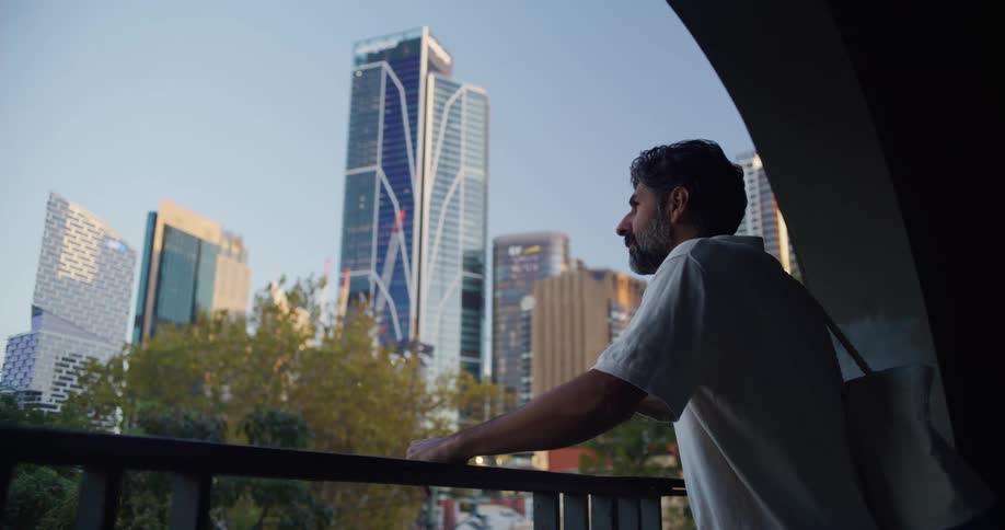 Man contemplating an urban skyline dominated by skyscrapers