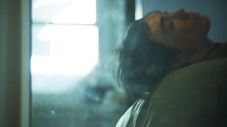 Man lying down on the bed and next to him legs of a naked woman