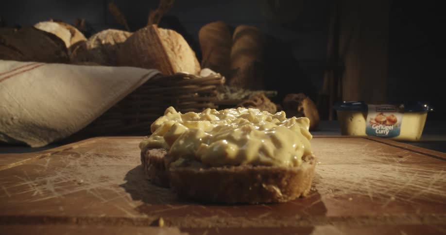 Person hand like a knife spreading cheese sauce on top of a slice of bread