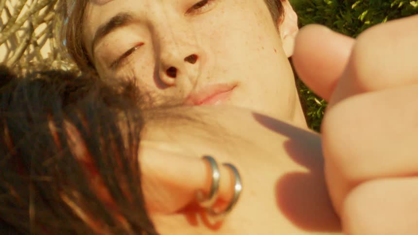 Portrait of a man lying down in an open environment and stroking his girlfriends face