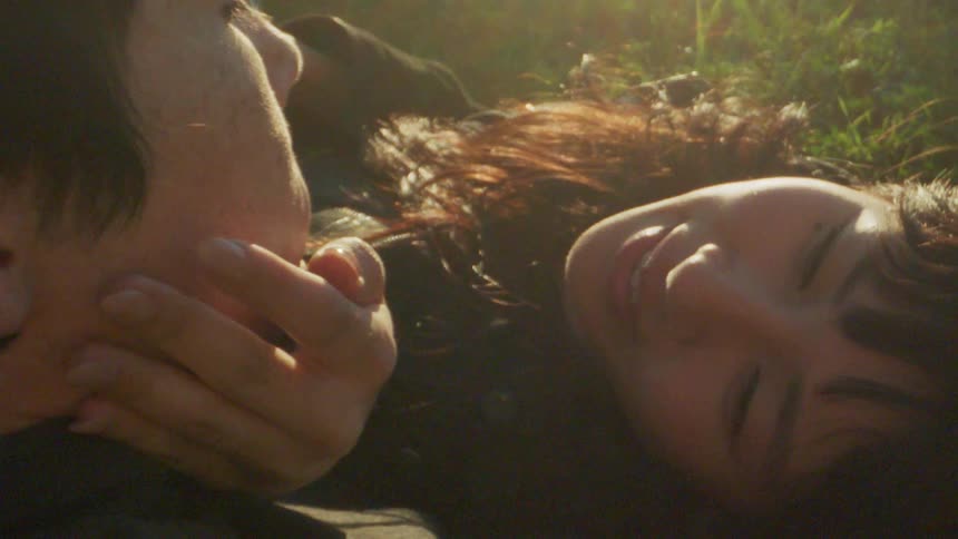 Portrait of a couple with a woman rubbing her boyfriends face while they are outdoors in sunlight