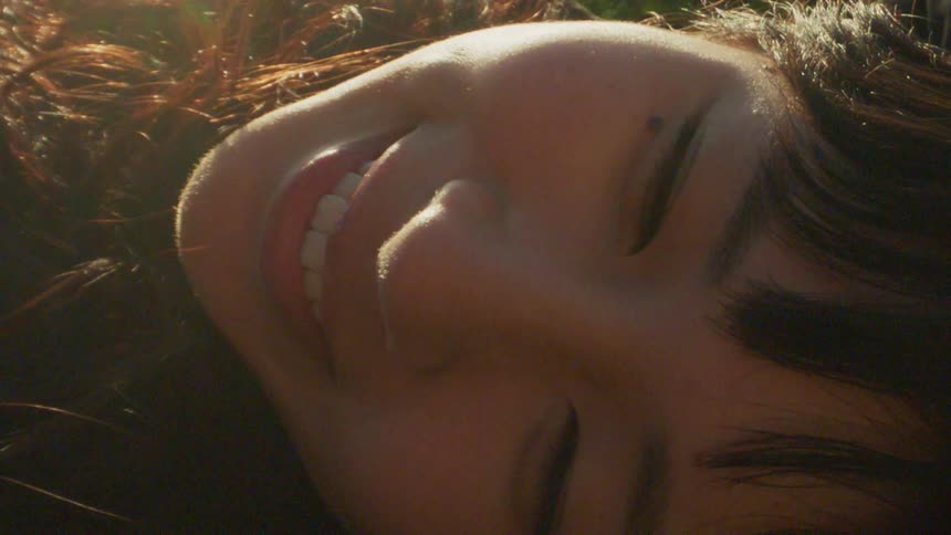 A woman smiles while lying in grass