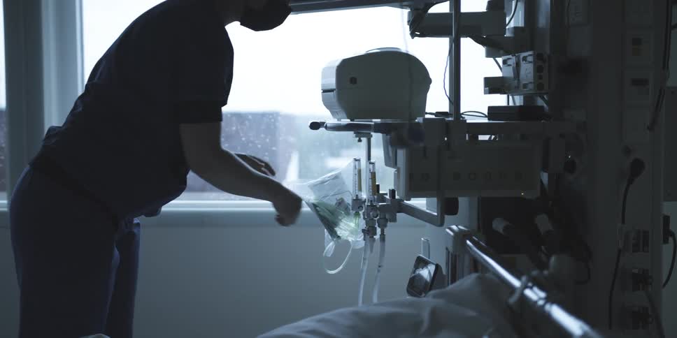 Healthcare professional in a hospital environment adjusting equipment at the bedside