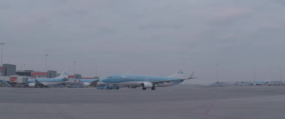 Blue plane reversing into an airport on a cloudy day