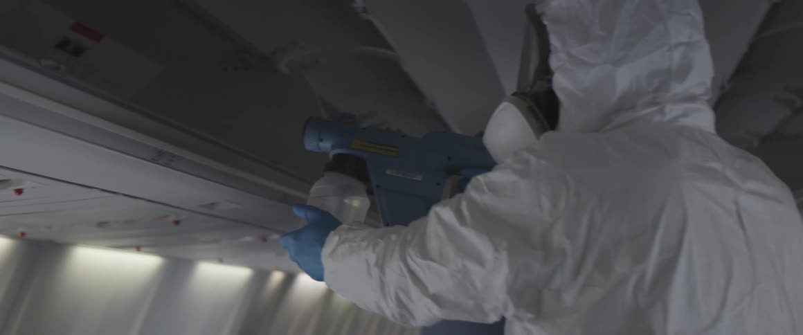 Person in protective clothing disinfecting an airplane inside
