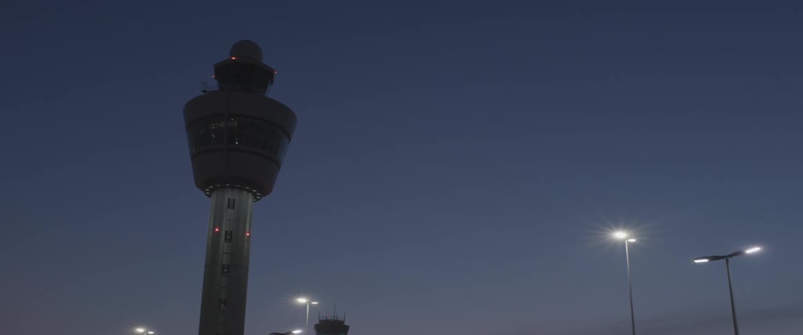 An air traffic control tower stands against a twilight sky