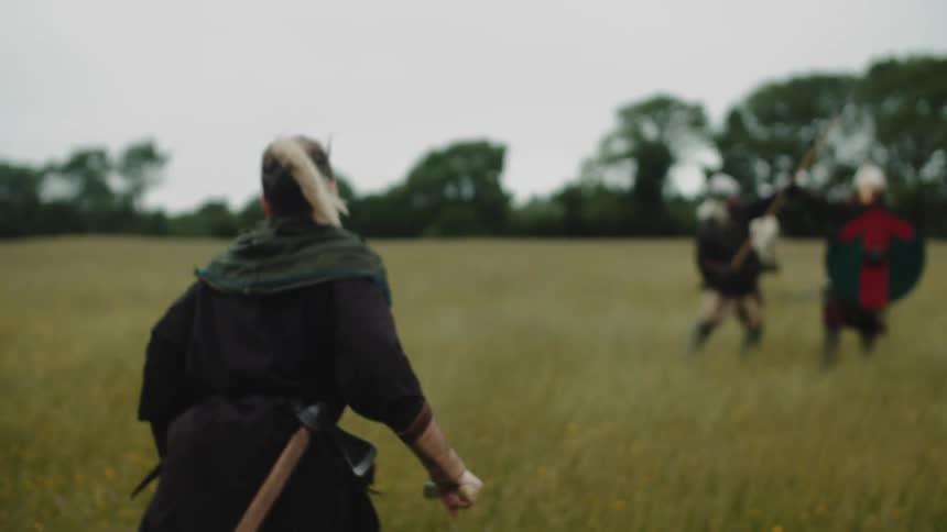 Woman running with a knife towards two soldiers fighting in an open field