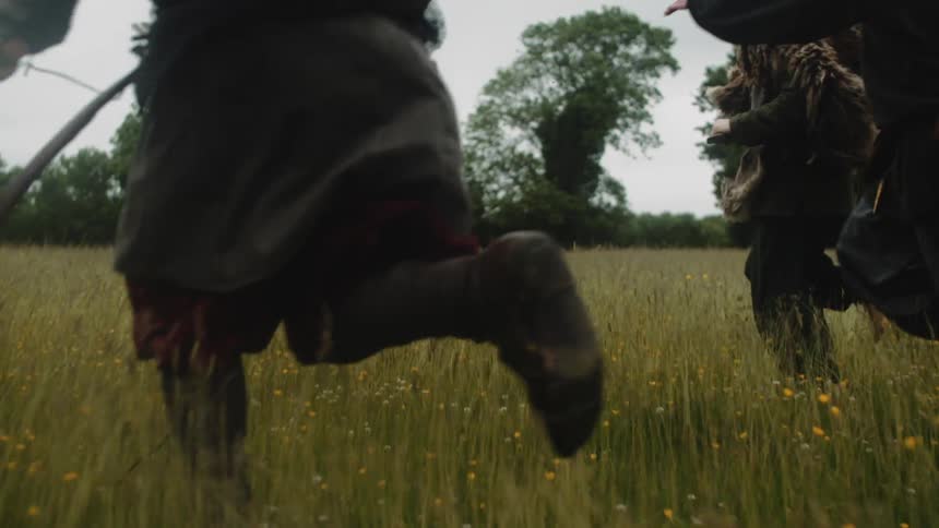 Three people running in a field of tall grass