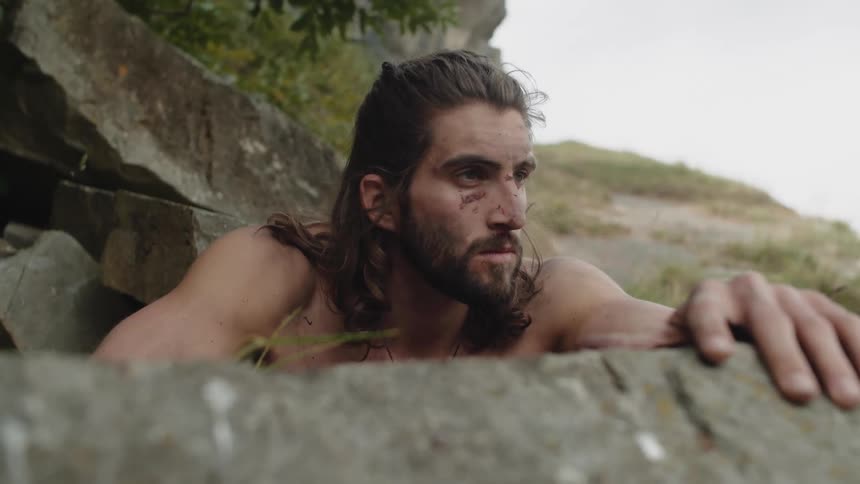 Portrait of a man with a serious facial expression and shirtless among rocks in a natural environment