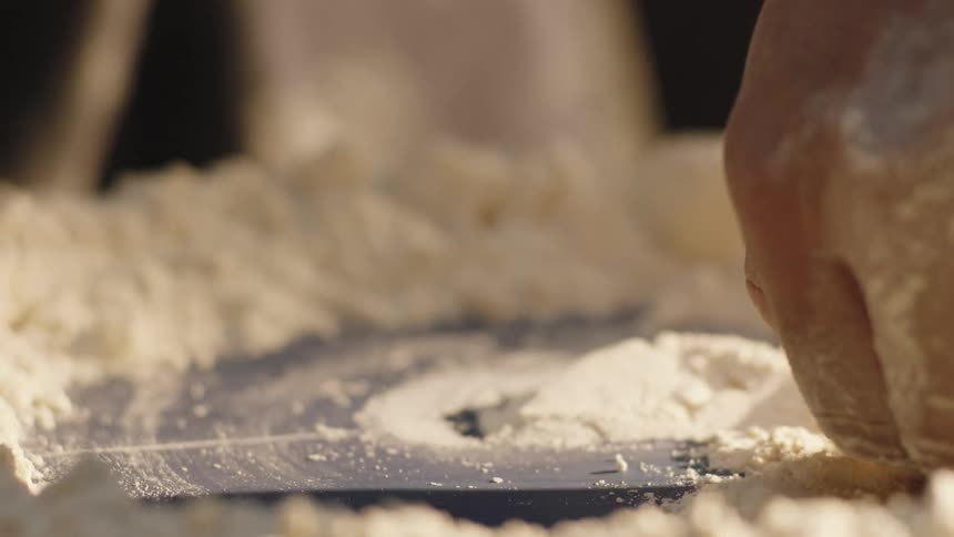 Closeup of a hand stirring in flour creating a hole in the middle