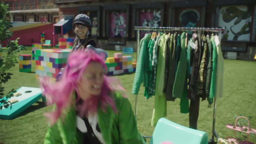 A woman walks through clothing set up in the park