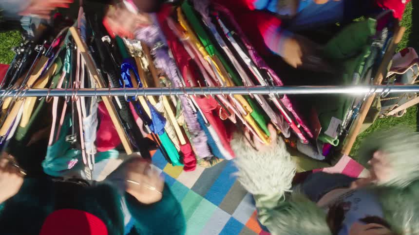 Clothes on a clothesline with hangers and women moving around