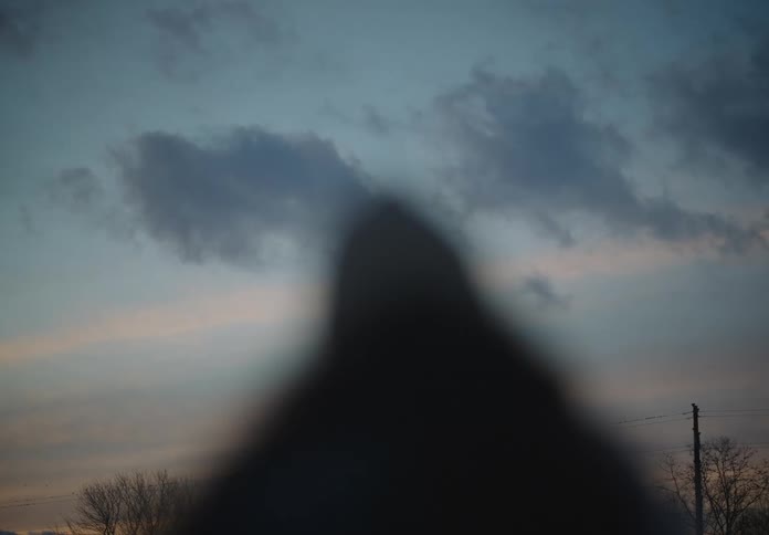 Silhouette of a person with their back against a calm morning sky