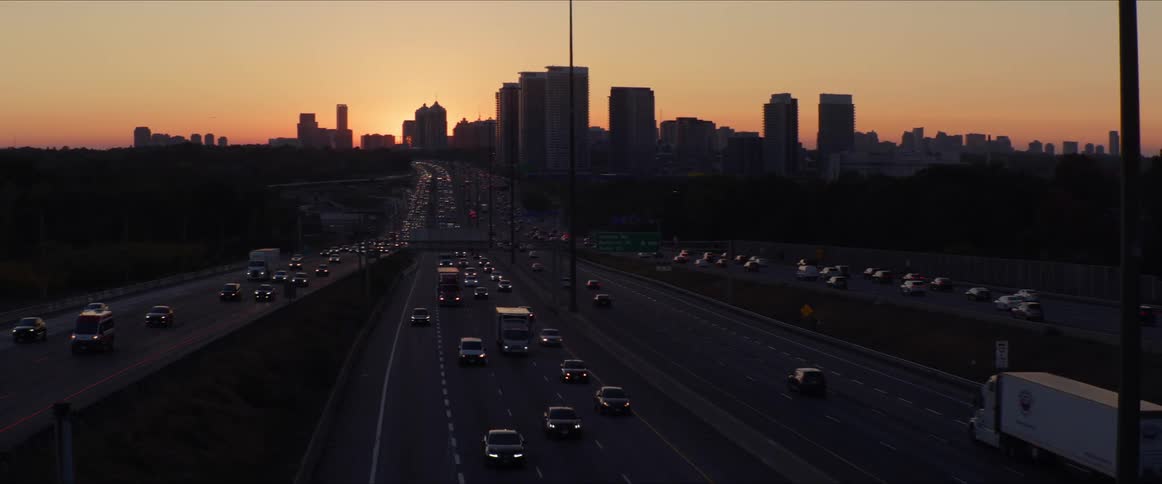 Panorama of highways with vehicle traffic and in the background the silhouette of a metropolis in the late afternoon