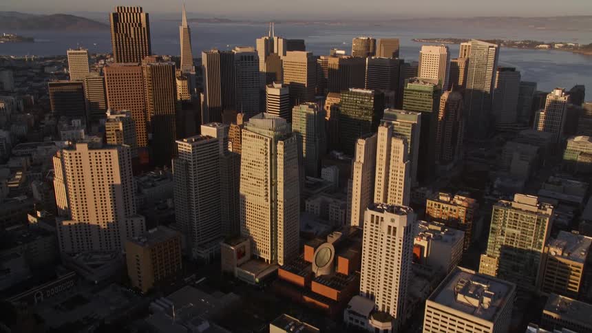 Vehicles move through the shadowed streets of a coastal city