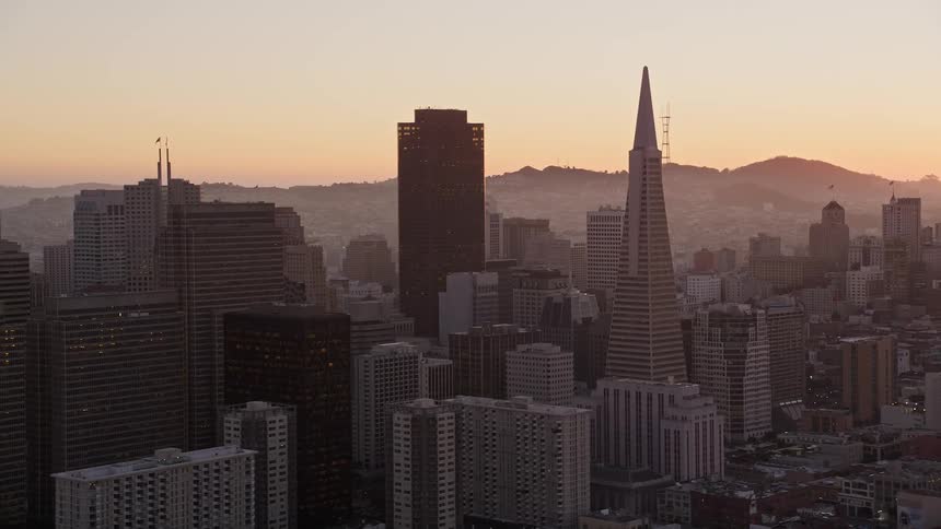 Aerial panorama of a metropolis with large buildings and the silhouette of mountains on the horizon on a morning with a red sky