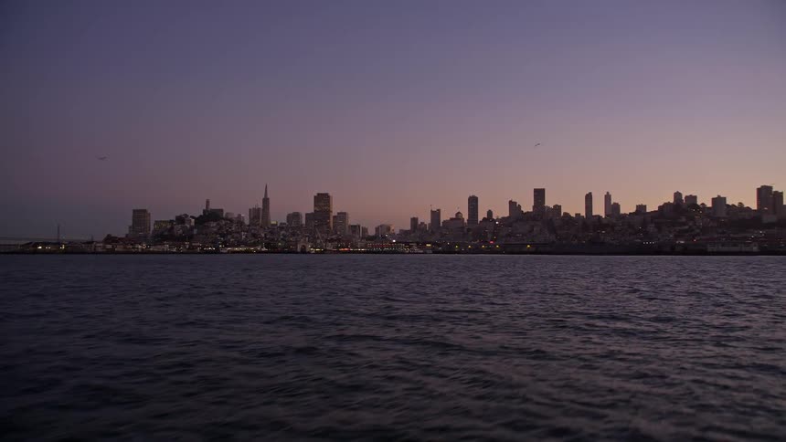 Coastal city skyscrapers contrast with lavender and pink sky during the evening