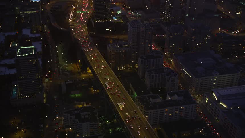 Aerial panorama of an illuminated metropolis and an overpass with heavy vehicle traffic in a purple night sky