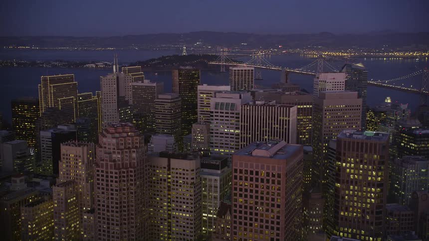Aerial scene of a metropolis with skyscrapers by the sea and illuminated at night with an extensive bridge connecting the cities