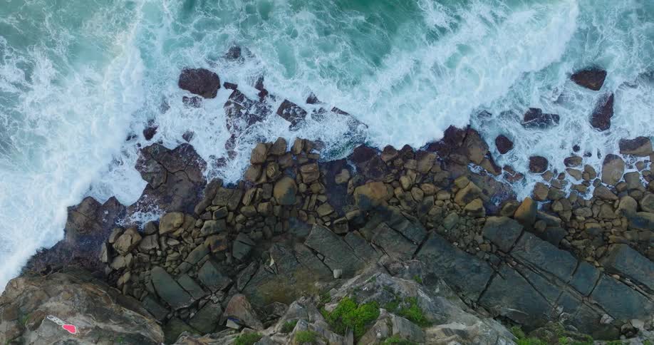 Aerial view of the sea with waves crashing onto a rocky shore