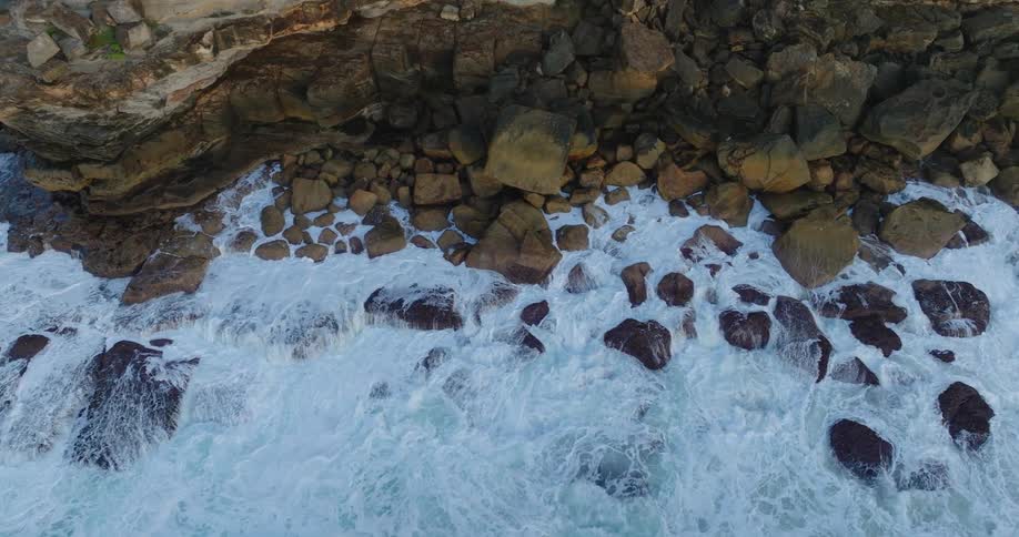 Aerial view of the sea with waves crashing onto a rocky shore