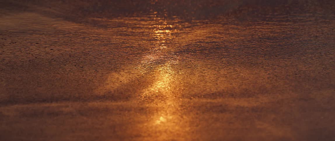 A golden sunset reflecting on a rippled water surface