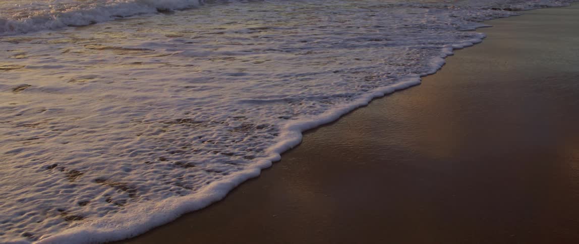 Waves foam while flowing onto a sandy beach