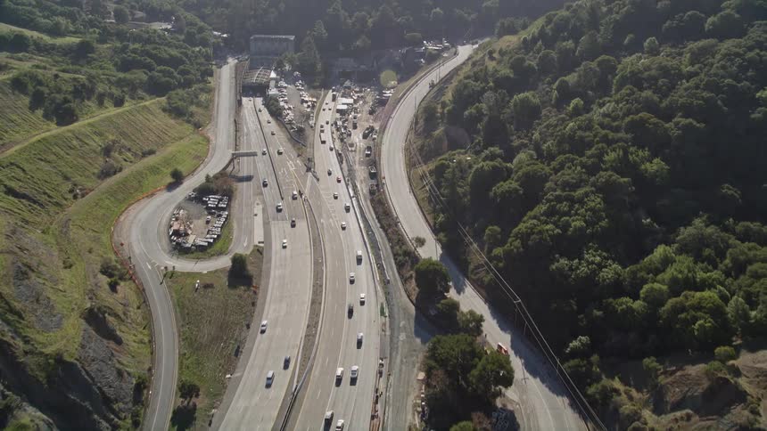 Aerial panorama of highways in opposite directions with vehicle traffic and surrounding wooded mountains