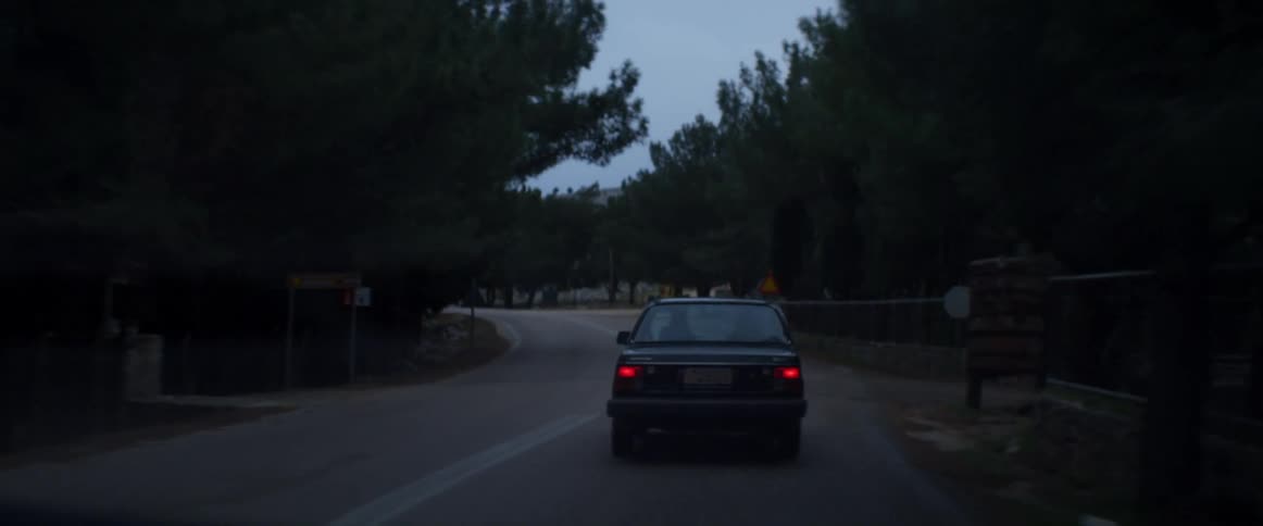 A car travels down a road at dusk