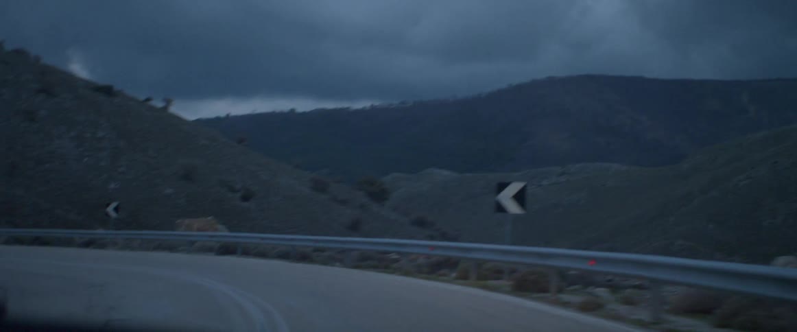 Driving along a twisted road past some hills
