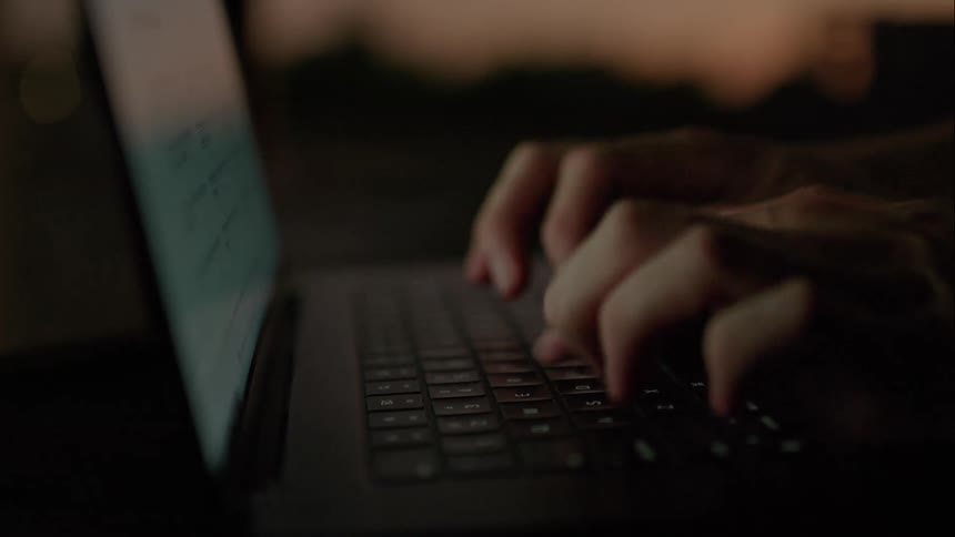 The hands of a person who is typing quickly on a laptop keyboard