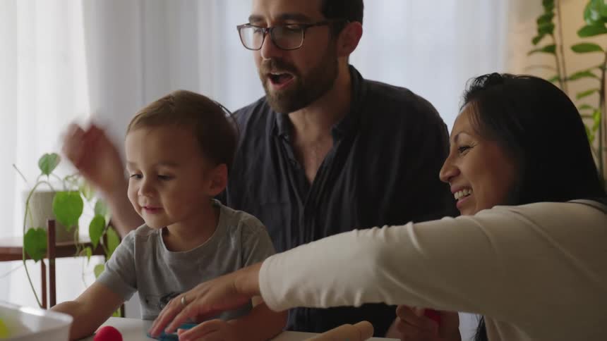 Family with parents playing with their little son at a table with educational clay