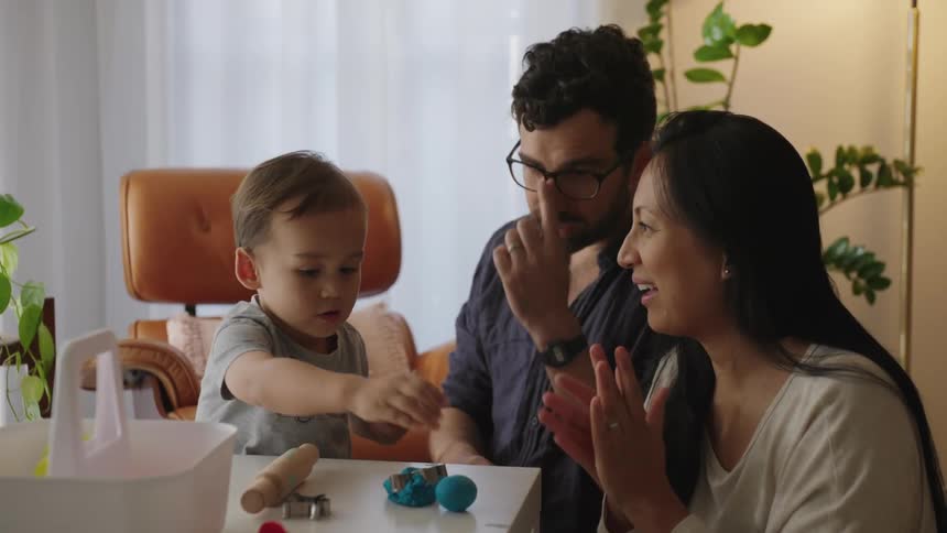 Parents playing with their child on a table with modeling clay