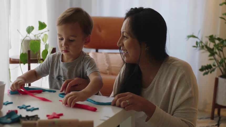 Mother playing with her son on a table with modeling clay