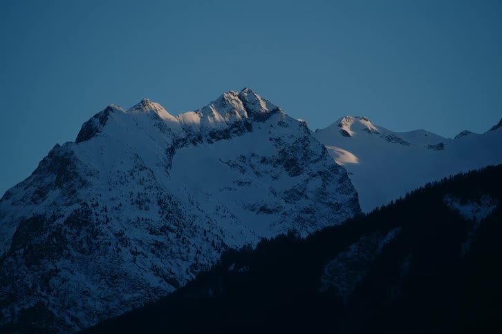 Wooded mountain covered in snow on a darkening day