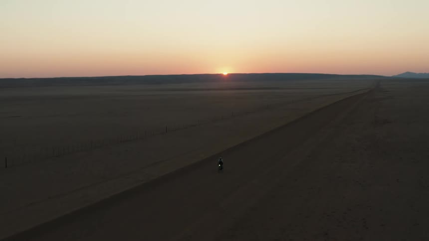 A motorcycle rides off road at sunrise