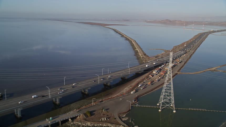 Traffic moves over a long bridge near a coast