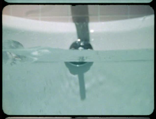 An adults hand splashes water in a bathtub