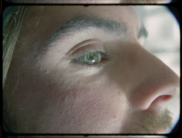 Side portrait of a man with green eyes with reflection of sunlight with water on his face