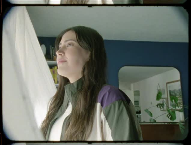 Wind blows the curtain as a woman looks outside
