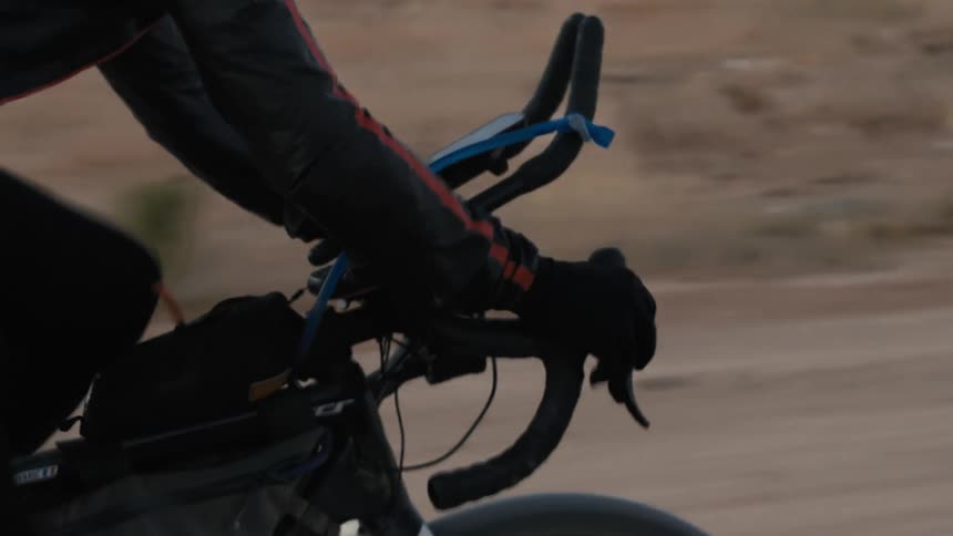 Hands of a person pedaling a bicycle on a dirt road at high speed