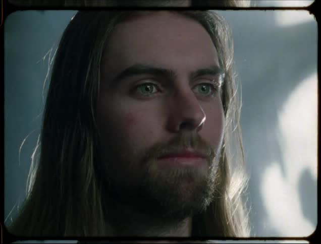 Man smiles as he stares while shadows play in the background