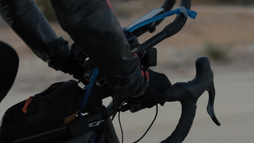 Closeup of the gloved hands of a cyclist pedaling in an outdoor environment during the day