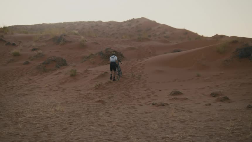 A clip of a person walking a bike in the desert
