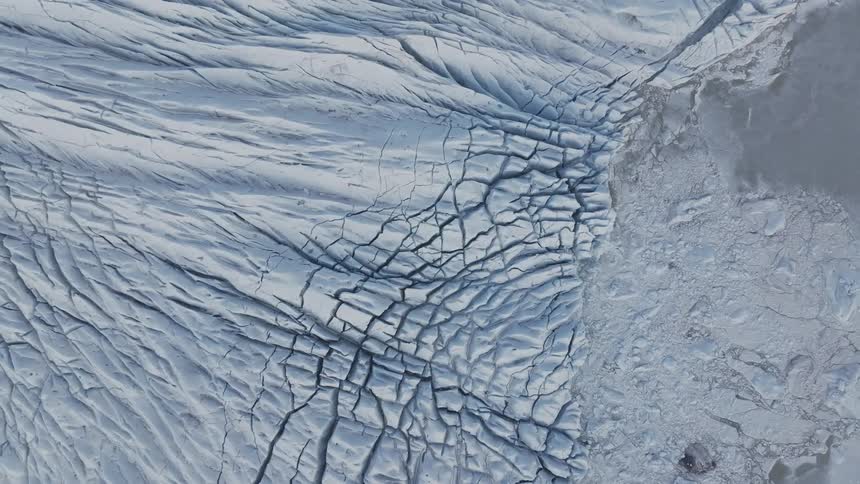 An aerial view of a snowy ground with several cracks