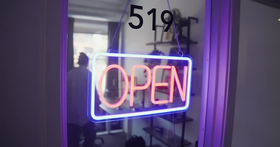 A woman turns on an open sign for a business