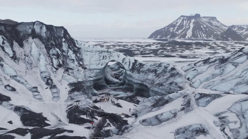 Panorama of adventurers on a plateau in the middle of snowcovered mountains on a cloudy day