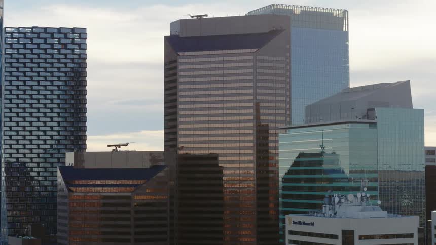 Movement across many tall buildings with reflective windows in the daytime